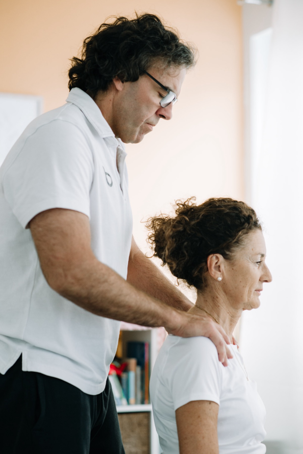 Physiotherapeut behandelt eine Patientin bei beyond in Bozen – gezielte Handgriffe an Schulter und Nacken.