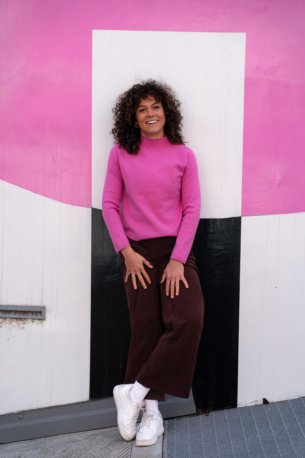 Johanna Fischer steht vor einer pink-weißen Wand in Bozen und lächelt in die Kamera.
