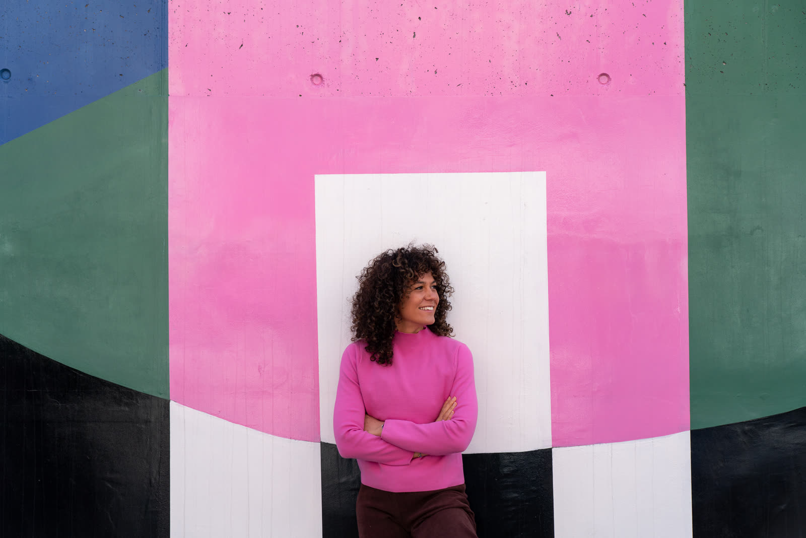 Johanna Fischer lehnt lächelnd an einer bunt bemalten Wand in Bozen.